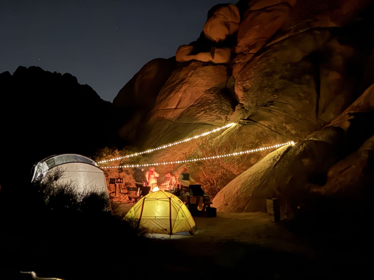 Tents lit up at night beneath large rocks in Joshua Tree National Park